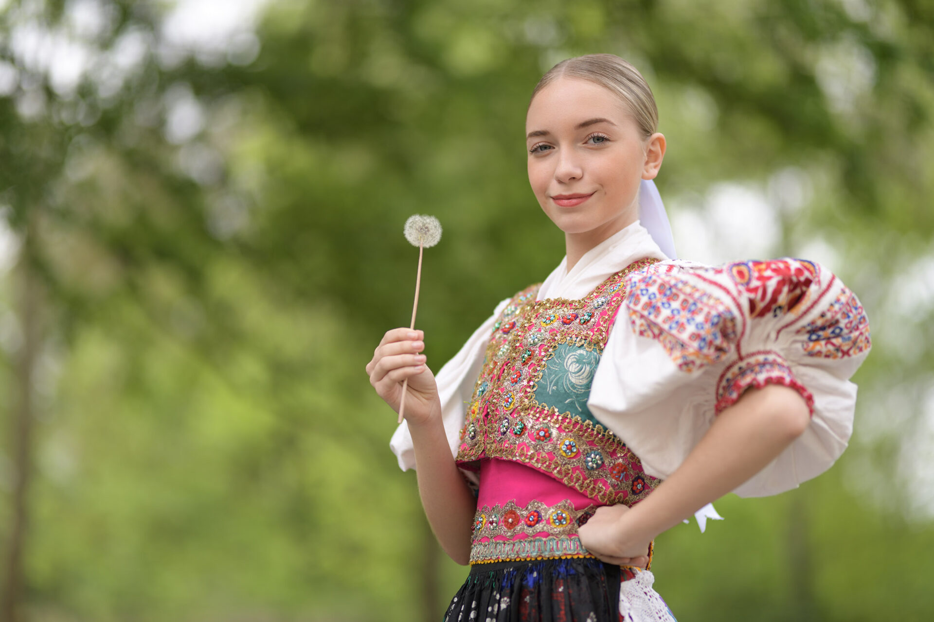 Dame in Slovaaks folklore kostuum met een paardenbloem in haar hand