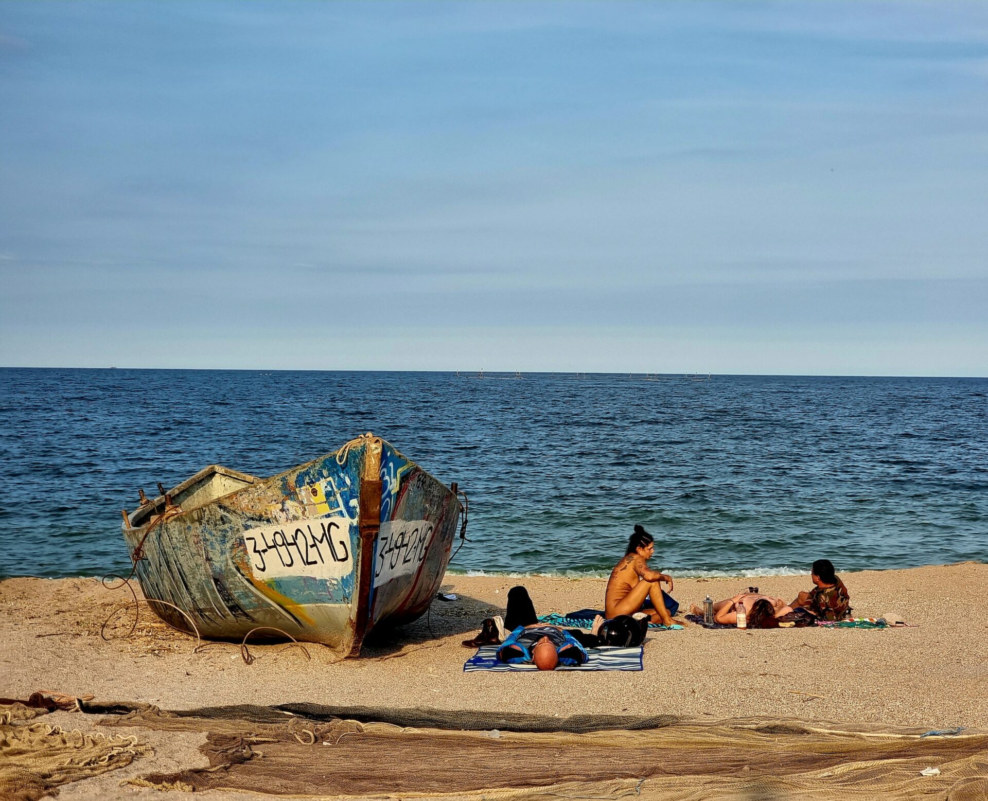 Een boot en zonnebadende mensen op het strand van Vama Veche